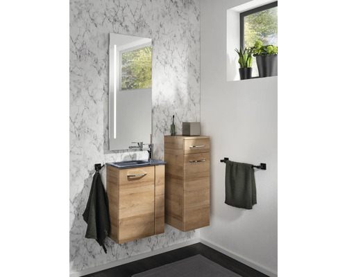 Salle de bains moderne avec meuble sous-lavabo et meuble d'appoint aspect bois devant un mur effet marbre avec miroir éclairé.