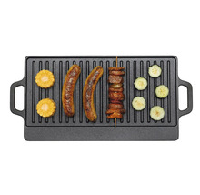 Plaque de grillade en fonte avec saucisses, maïs, brochette de viande et rondelles de courgettes.