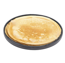 Stapel dünner Pfannkuchen auf einem runden schwarzen Teller.