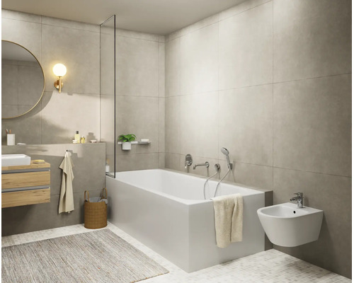 Modernes, helles Badezimmer mit weißer Badewanne, wandhängendem Bidet, Waschtisch mit Holzfront, rundem Spiegel und grauen Wandfliesen.