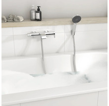 Mitigeur de baignoire moderne en chrome avec douchette dans une baignoire blanche avec mousse.