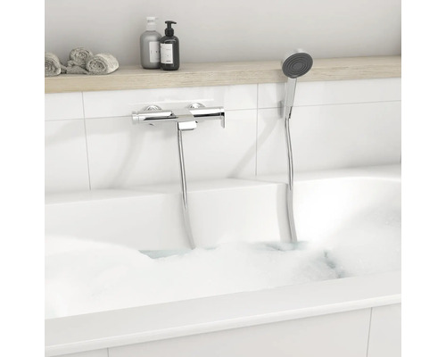 Mitigeur de baignoire moderne en chrome avec douchette dans une baignoire blanche avec mousse.