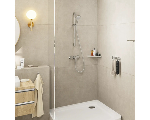 Modernes, helles Badezimmer mit Glasdusche, verchromten Armaturen, beigen Wandfliesen und einem Unterschrank aus Holz.