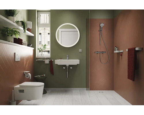 Modernes Badezimmer mit wandhängendem WC, Waschbecken, rundem Spiegel, ebenerdiger Dusche, Regalen und Zimmerpflanzen.