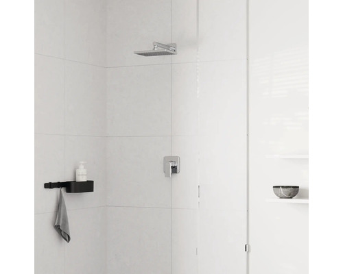 Douche moderne avec pomme de douche carrée en chrome, mitigeur monocommande et étagère de douche noire sur mur carrelé clair.