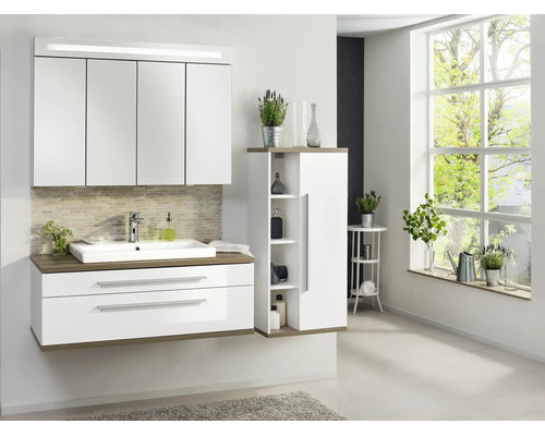 Ensemble de salle de bains moderne avec meuble sous-vasque blanc, armoire de toilette éclairée et meuble latéral aspect bois dans une pièce lumineuse.