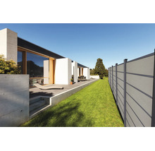 Moderner Sichtschutzzaun aus Paneelen neben Rasenfläche und Terrasse eines zeitgenössischen Hauses mit großen Glasfronten.