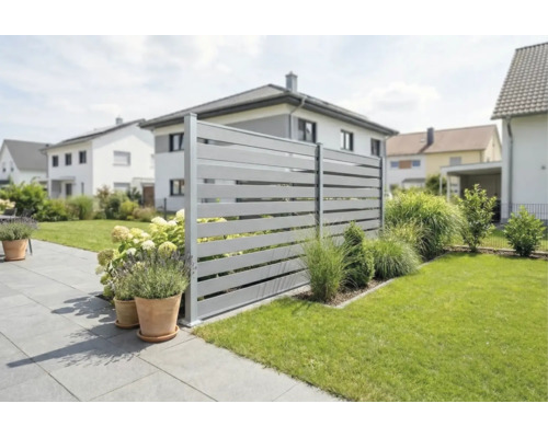 Clôture brise-vue moderne avec lattes horizontales grises dans un jardin soigné avec terrasse, pelouse et bacs à fleurs.