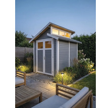 Abri de jardin moderne en bois gris avec bordures blanches, porte double vitrée et impostes dans un jardin éclairé.