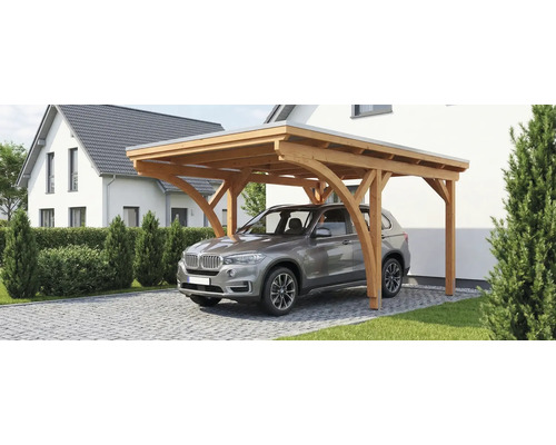 Abri de voiture en bois avec toit plat et poteaux cintrés, avec une voiture garée sur une allée pavée à côté d'une maison.