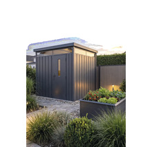 Abri de jardin moderne en métal avec toit plat et impostes dans un jardin aménagé avec un carré potager surélevé et un chemin en pierre.