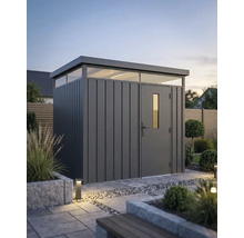 Abri de jardin moderne en métal avec toit plat et fenêtres imposte dans un jardin organisé avec des dalles en pierre et des plantes.