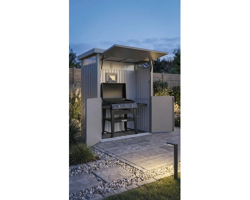 Metall-Grillschrank mit offenem Dach und Türen, darin ein Tenneker Gasgrill auf einer gepflasterten Terrasse im Garten bei Dämmerung.