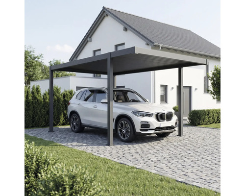 Moderner Metall-Carport in Anthrazit mit Flachdach, unter dem ein SUV auf einer gepflasterten Einfahrt vor einem Wohnhaus parkt.