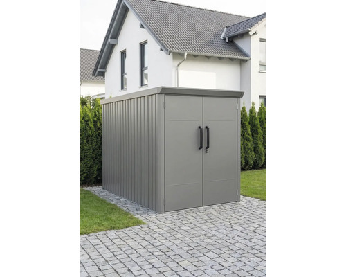 Abri de jardin moderne en métal avec double porte et toit plat, installé sur un pavage extérieur.