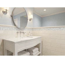 Salle de bains lumineuse avec meuble sous vasque blanc, plan en marbre, miroir ovale et carrelage mural type métro.