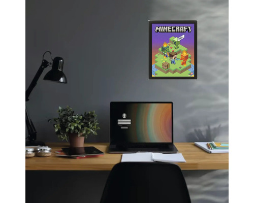 Poster Minecraft dans un cadre noir sur un mur sombre au-dessus d'un bureau avec un ordinateur portable et une plante.