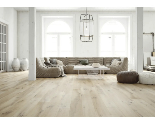 Heller, geräumiger Wohnraum mit hellem Holzfußboden, großem Modulsofa, weißem Couchtisch und großen Bogenfenstern.