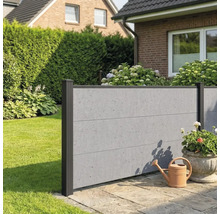 Clôture pare-vue moderne aspect béton avec poteaux foncés dans un jardin sur une terrasse en pierre avec un arrosoir.