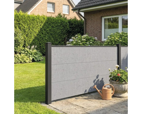 Clôture pare-vue moderne aspect béton avec poteaux foncés dans un jardin sur une terrasse en pierre avec un arrosoir.