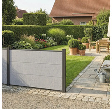 Clôture pare-vue moderne aspect béton dans un jardin avec pelouse, massifs et une terrasse pavée avec des meubles en bois.