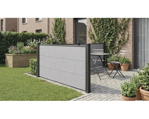 Brise-vue moderne aspect béton sur une terrasse pavée à côté d une pelouse, avec coin salon et mur en briques végétalisé.