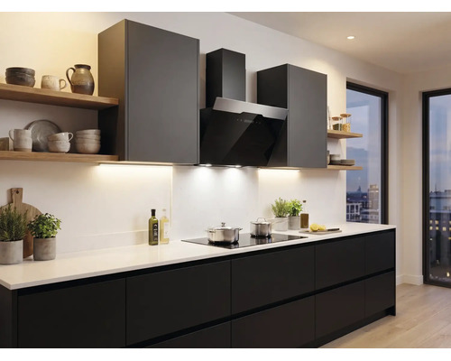 Cuisine moderne avec façades sombres, plan de travail blanc, hotte aspirante noire et étagères en bois.