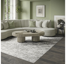Modernes, helles Wohnzimmer mit einem großen grau-weiß gemusterten Teppich, einem geschwungenen cremefarbenen Sofa und einem hölzernen Couchtisch.