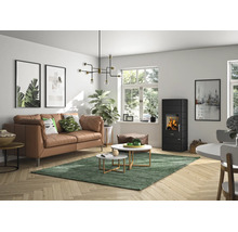 Salon moderne et lumineux avec poêle à bois noir, canapé en cuir marron, tables basses sur tapis vert et parquet en bois.