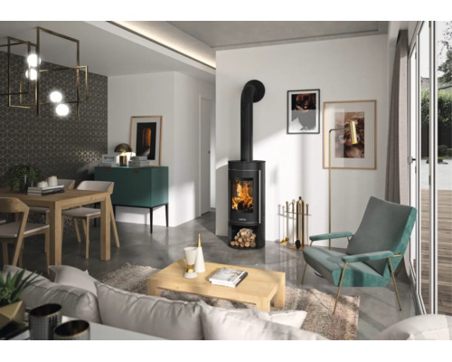 Salon moderne avec un poêle à bois noir avec feu apparent, une table en bois, un fauteuil turquoise et de grandes baies vitrées.