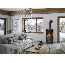 Poêle à bois moderne dans un salon lumineux avec vue sur un paysage hivernal enneigé à travers une grande fenêtre en bois.