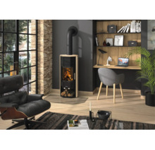 Poêle à bois moderne avec revêtement en grès et feu visible dans un salon clair et organisé avec fauteuil et bureau.