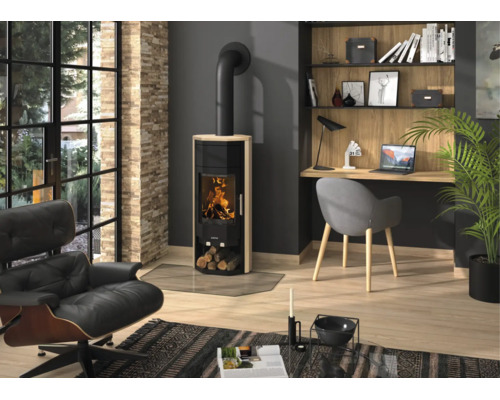 Poêle à bois moderne avec revêtement en grès et feu visible dans un salon clair et organisé avec fauteuil et bureau.