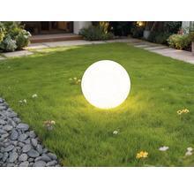 Lampe boule d'extérieur blanche lumineuse sur une pelouse verte dans un jardin.