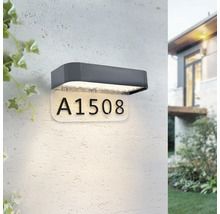 Applique murale extérieure LED avec panneau de numéro de maison éclairé sur un mur blanc texturé.
