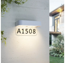 Lampe LED moderne pour numéro de maison avec boîtier blanc et panneau éclairé pour le numéro de maison, montée sur un mur extérieur.