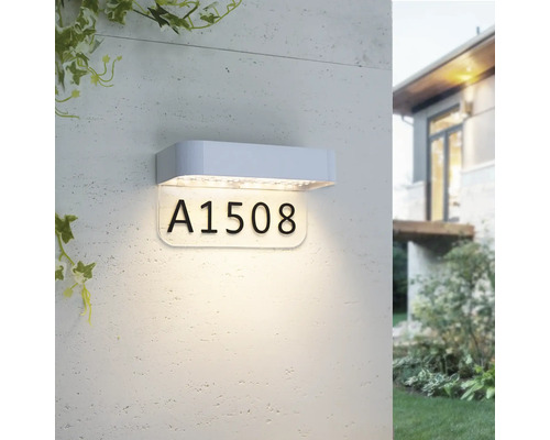 Lampe LED moderne pour numéro de maison avec boîtier blanc et panneau éclairé pour le numéro de maison, montée sur un mur extérieur.
