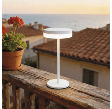 Lampe de table à LED blanche moderne sur une rambarde de balcon en bois à l'extérieur avec vue sur la mer.