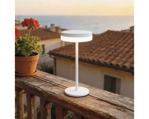 Lampe de table à LED blanche moderne sur une rambarde de balcon en bois à l'extérieur avec vue sur la mer.
