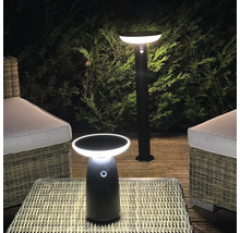 Éclairage extérieur LED moderne comprenant une borne lumineuse et une lampe de table sur une terrasse en bois avec des meubles en rotin.