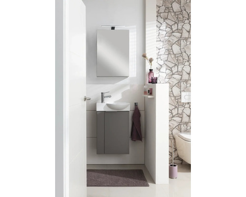 Modernes Gäste-WC Set mit grauem Unterschrank, weißem Waschbecken, Spiegel mit Beleuchtung und Natursteinwand.