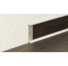 Silbernes Sockelleistenprofil aus Metall mit Einlage in dunkler Holzoptik am Übergang von Wand zu Boden.