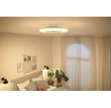 Moderner Deckenventilator mit integrierter Beleuchtung in einem hellen, modern eingerichteten Schlafzimmer mit Bett und Zimmerpflanze.