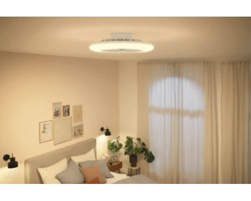 Moderner Deckenventilator mit integrierter Beleuchtung in einem hellen, modern eingerichteten Schlafzimmer mit Bett und Zimmerpflanze.