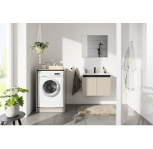 Salle de bain moderne et lumineuse avec meuble sous-vasque, miroir et lave-linge intégré dans un meuble.