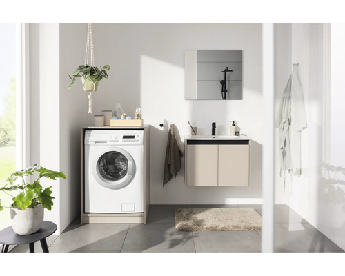 Salle de bain moderne et lumineuse avec meuble sous-vasque, miroir et lave-linge intégré dans un meuble.