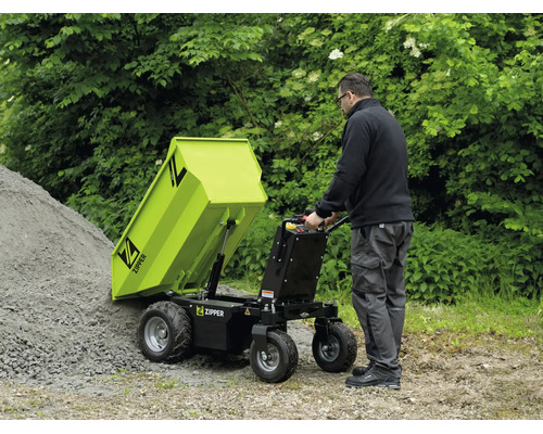 Ein Mann entleert einen Zipper Minidumper mit Kippvorrichtung auf einen Schotterhaufen im Garten. Funktionale, helle Außenanlage. Zipper Logo.
