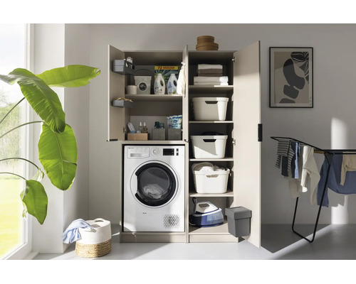 Armoire de buanderie beige avec lave-linge, portes ouvertes, étagères, paniers à linge et lessive dans une pièce lumineuse.