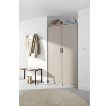 Armoire de couloir beige moderne à deux portes, avec un banc de vestiaire et un tapis rond dans une entrée lumineuse.
