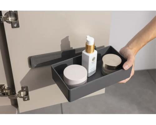 Une boîte de rangement grise avec des cosmétiques est suspendue à un support à l'intérieur d'une porte de placard.